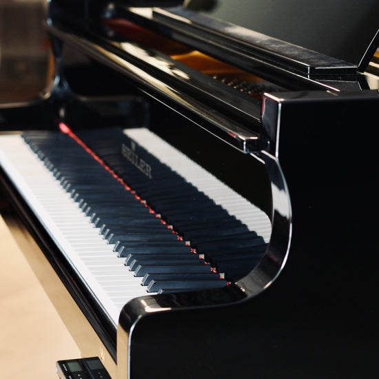 Vue de côté du Seiler 206 noir brillant, piano à queue d’occasion disponible chez Accord & Co
